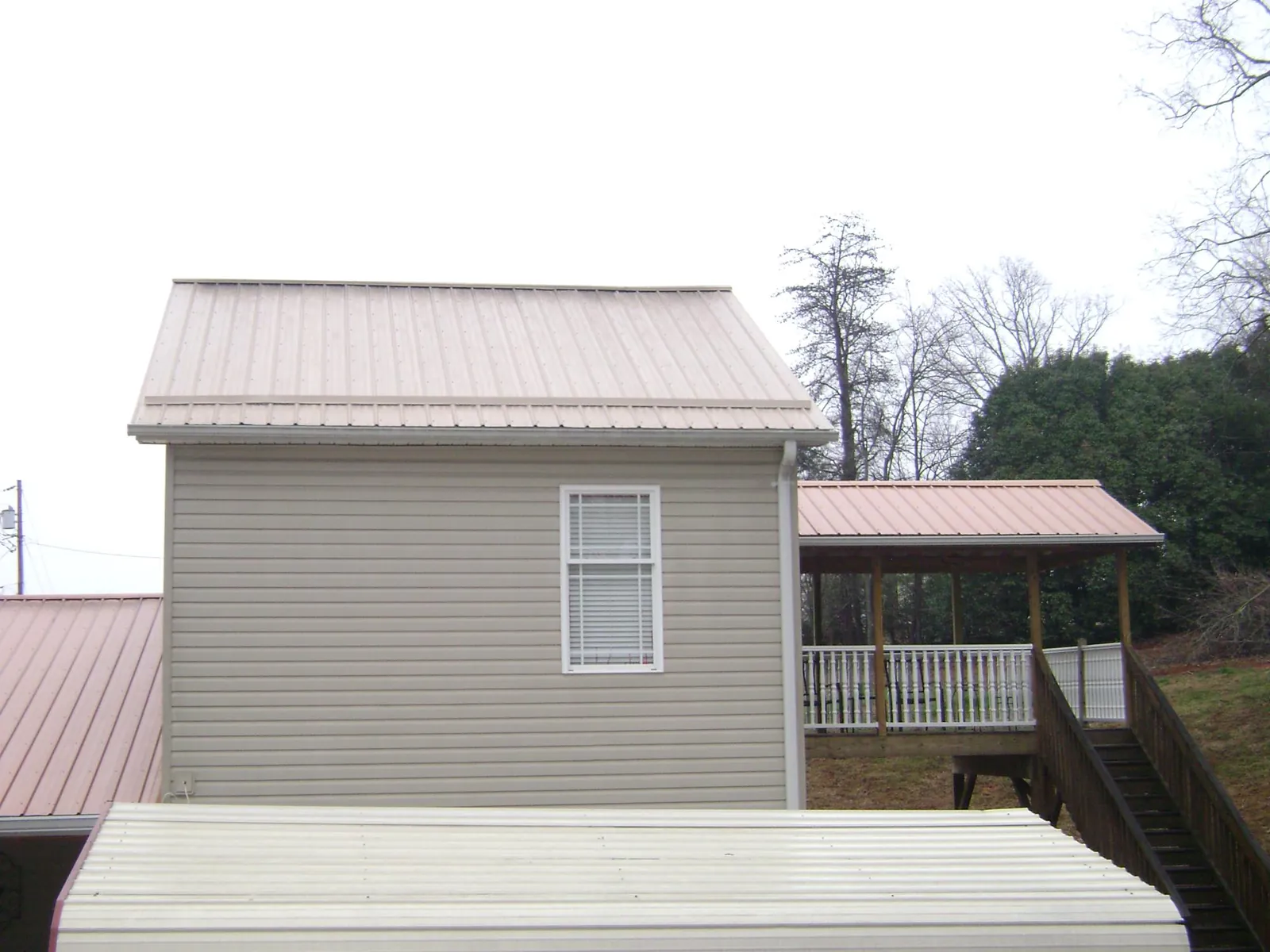 Tan metal roofs on a two story addition and attached porch, from a Roof Replacement job in Buchanan